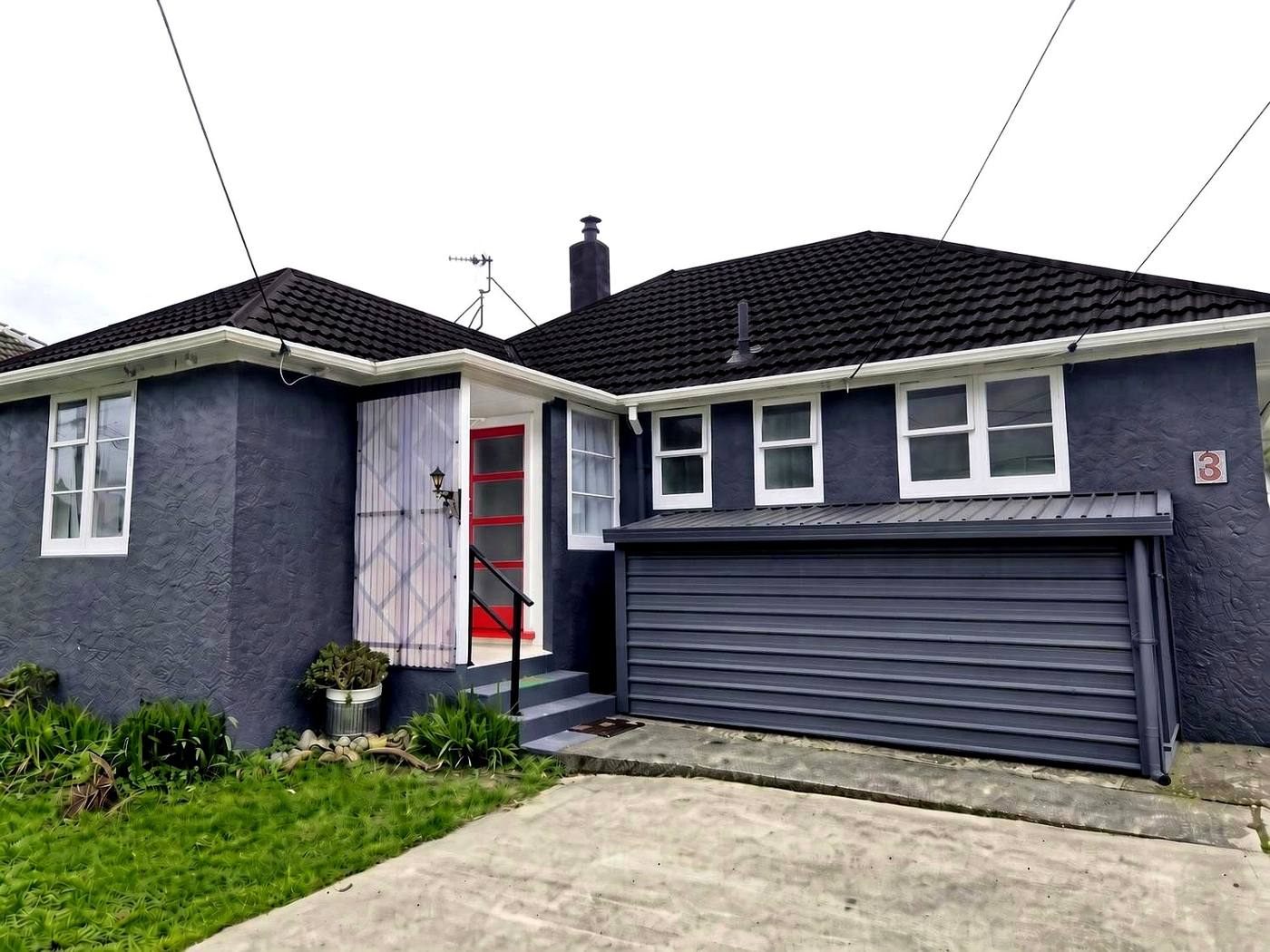 Grey bungalow with a new tile roof and red door