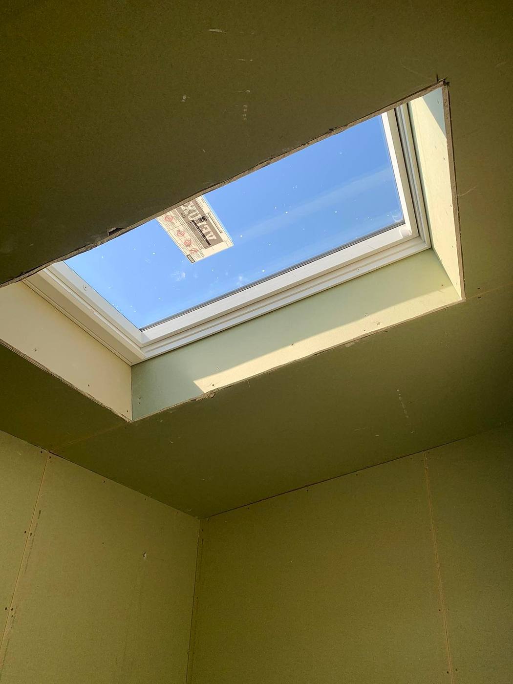 Looking up through a finished skylight and lined light well to blue sky