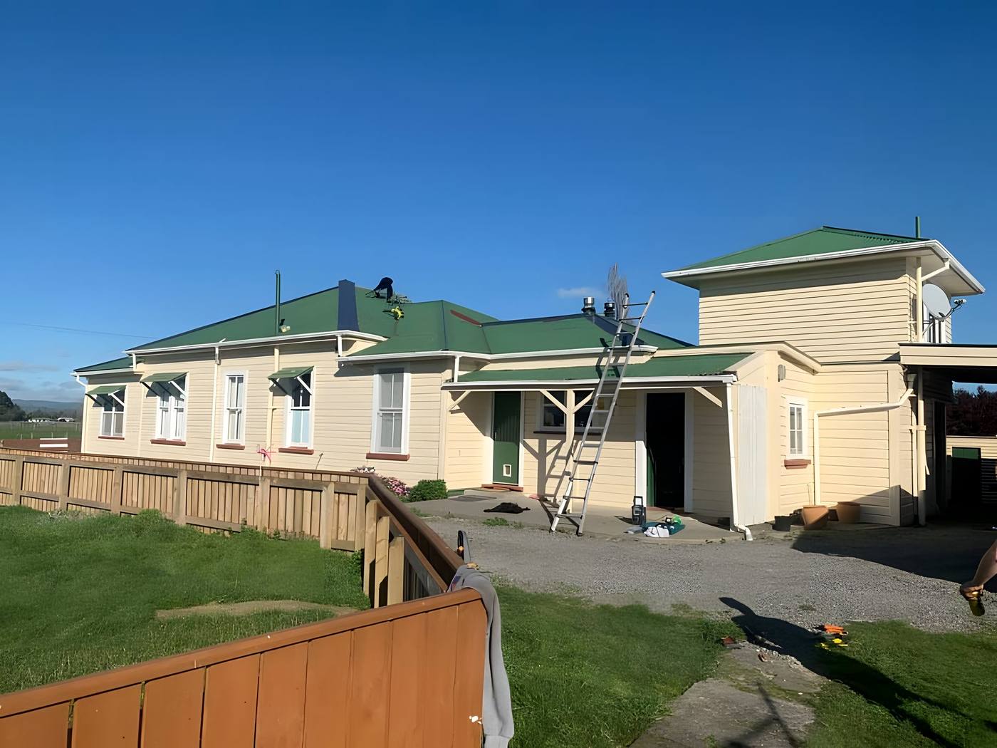 Villa with a freshly painted green roof and a ladder at the eaves
