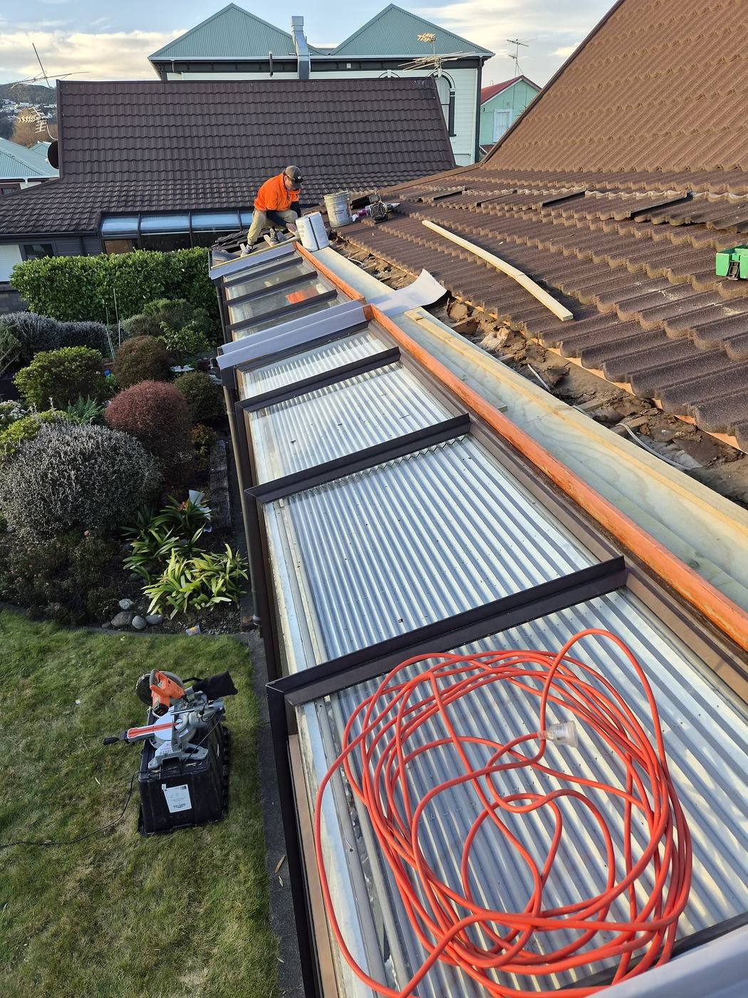 New long-run corrugated roof sheets and gutter beside an older tile roof