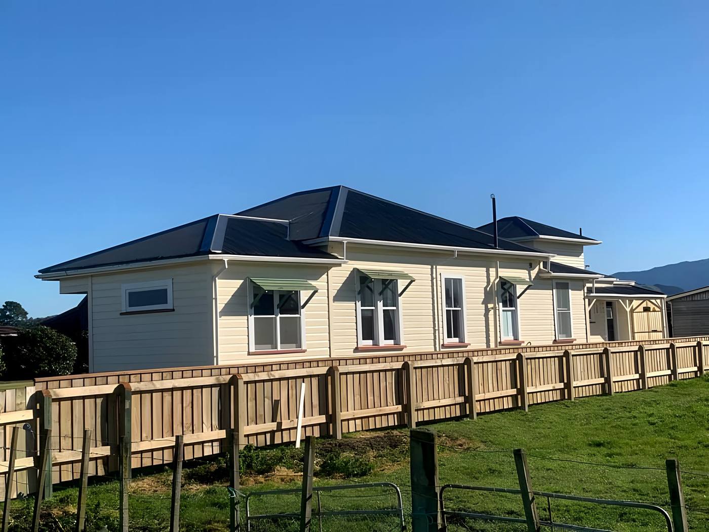 Weatherboard house with a freshly painted dark roof and new fence