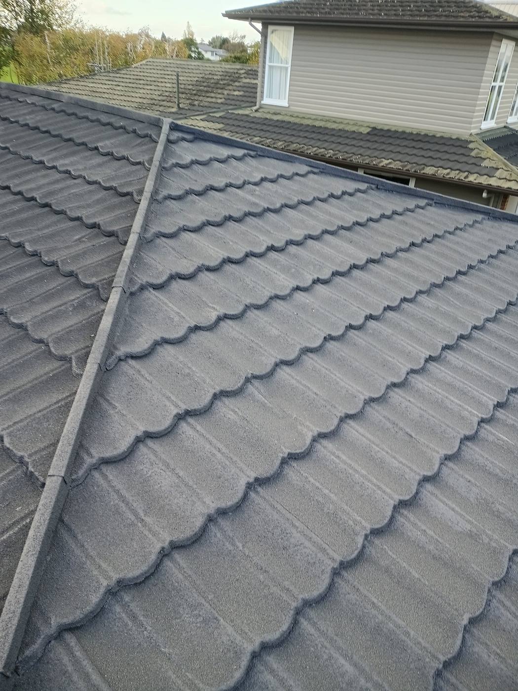 Close-up of a profiled concrete tile roof with ridge capping and gutter