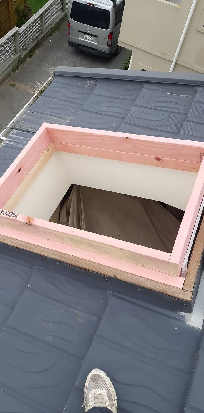 Skylight curb on a grey roof wrapped in flashing tape before the unit is fitted